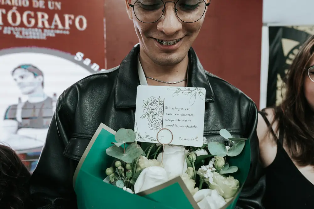 Un participante sonríe con un ramo de flores y una tarjeta de regalo